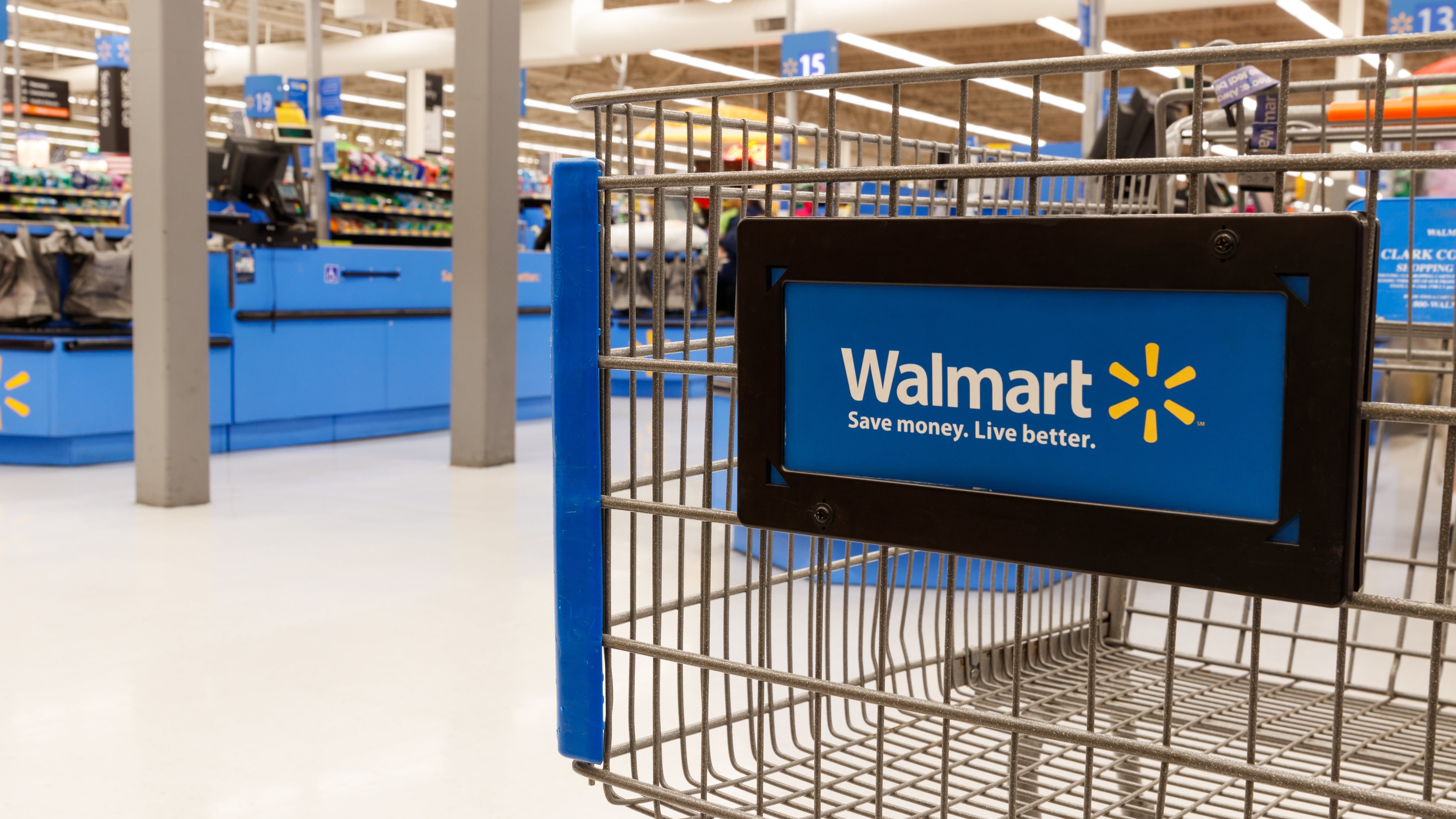 Inside a Walmart store, showing checkouts and a cart.